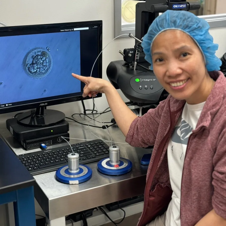 Person smiling and pointing at screen with an embryo on it