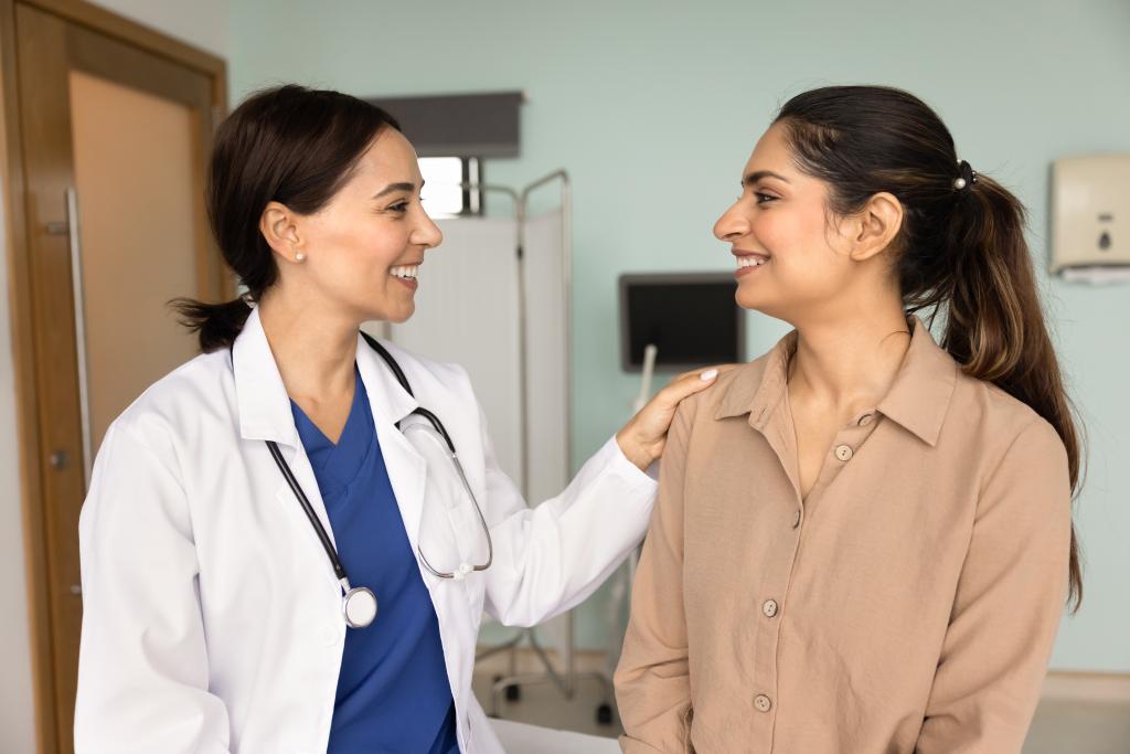 An NP and a fertility patient smile warmly at one another.