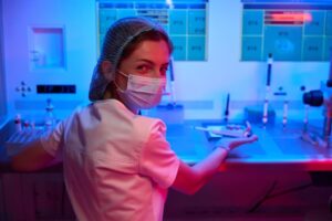 An embryologist at work smiles behind her medical mask.